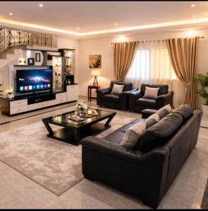 a living room with a leather couch and a tv at La Perle de Hergla Maison d Hotes in Harqalah