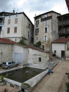 un vecchio edificio con una piscina d'acqua in un cortile di Faubourg St Jean ad Aubeterre-sur-Dronne