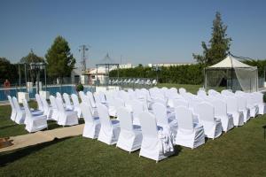 a row of white chairs sitting in the grass at Hotel Acosta Ciudad de la Música in Villafranca de los Barros