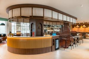 a restaurant with a bar with chairs and tables at Hampton by Hilton Bordeaux Merignac Airport in Mérignac