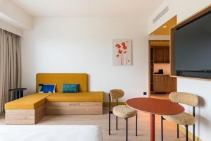 a living room with a couch and a table and chairs at Hampton by Hilton Bordeaux Merignac Airport in Mérignac