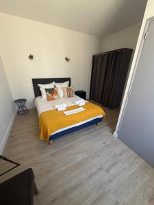 a bedroom with a large bed with a yellow blanket at Le central in Balaruc-les-Bains +1 photo