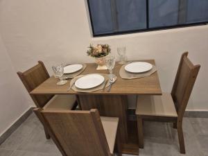 a wooden table with chairs and plates and wine glasses at Kitnet Vale do Amanhecer - Templo Mãe in Planaltina +8 photos