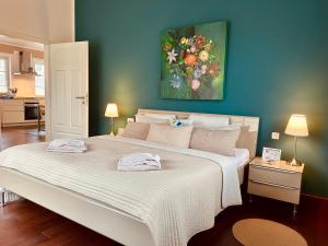 a bedroom with a large white bed with a painting on the wall at Strandquartier 31 "Quartier 2" in Wustrow
