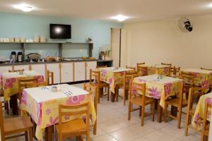 Pousada dos Sonhos في انغرا دوس ريس: غرفة طعام مع طاولات وكراسي ومطبخ