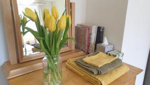 a vase of yellow tulips sitting on a table with a mirror at 15 Kershaw Crescent in Luddenden Foot