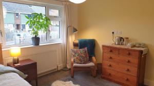 a bedroom with a chair and a dresser and a window at 15 Kershaw Crescent in Luddenden Foot