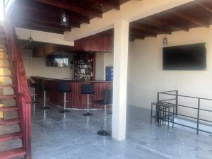 a bar in a building with chairs and a television at Comfortable and affordable in Saint Georgeʼs
