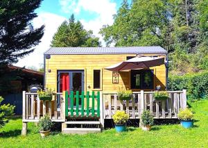 a tiny house with a porch and two green chairs at Tiny somniflore in Wasigny