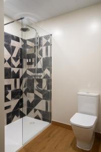 a bathroom with a toilet and a glass shower at Casa Carver 1927 by Hommyhome in Seville