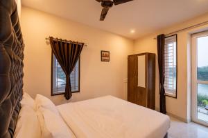 a bedroom with a bed and two windows at Aafiya lakeview Apartments in Coimbatore