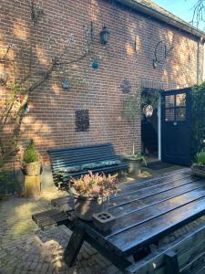 a wooden bench sitting in front of a brick building at In het koetshuis in Apeldoorn