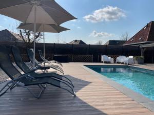 a pair of chairs and an umbrella next to a pool at Hoeve Altena Barn in Woudrichem
