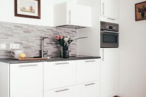 a white kitchen with white cabinets and flowers in a vase at Haus Luna - Apartment Luna 6 in Schwangau
