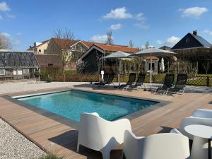 a swimming pool with chairs and umbrellas in a yard at Hoeve Altena Barn in Woudrichem