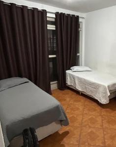 a bedroom with two beds and a window at Quarto individual Aconchego in Divinópolis