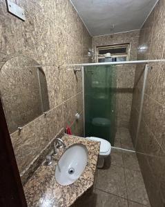 a bathroom with a sink and a shower and a toilet at Quarto individual Aconchego in Divinópolis