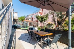 a wooden table and chairs with an umbrella on a sidewalk at Apartment Petar in Kaštela