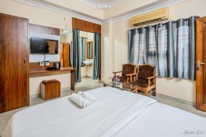 a bedroom with a large white bed and a chair at Laxman Avenue in Jagdalpur