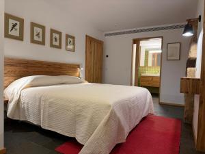 a bedroom with a white bed with a red rug at Casa Vidinha in Faria de Baixo +25 photos
