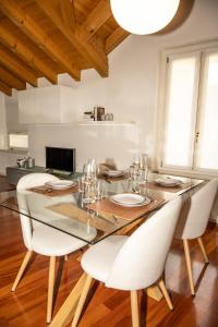 a dining room with a glass table and white chairs at Liberty Apartment in Lovere