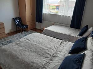 a bedroom with two beds and a chair and a window at Ceecliff House in Culdaff