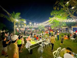 a crowd of people at a party at night at Con Nho RiverHouse Hue in Thôn Tiên Nộn