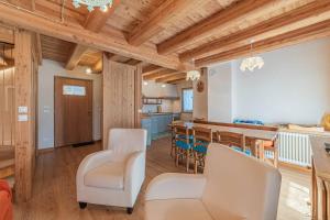 a kitchen and dining room with wooden ceilings and white chairs at Chalet Dolomites Heart in Feder
