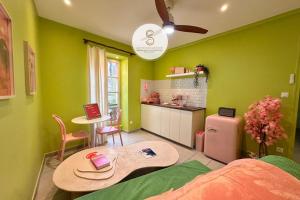 a bedroom with green walls and a table and a kitchen at Arles Getaway - Le Flamant Vert in Arles