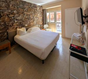 a bedroom with a large bed and a stone wall at Hostal Mar del Plata in El Arenal