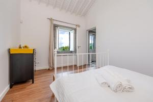 a white bedroom with a bed and a window at Casas do Forneiro - T2 in Nordeste +42 photos