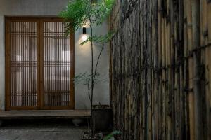 a plant in a pot next to a building with a door at 杭州喜在山舍 in Qingshandian