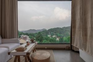 a living room with a large window and a couch at 杭州喜在山舍 in Qingshandian
