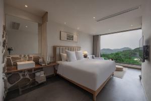 a bedroom with a large white bed and a large window at 杭州喜在山舍 in Qingshandian +45 photos