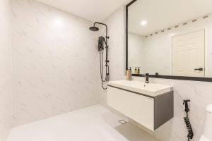 a white bathroom with a sink and a mirror at The Mellow at Sathorn in Chinatown
