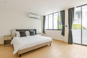 a white bedroom with a large bed and windows at The Mellow at Sathorn in Chinatown