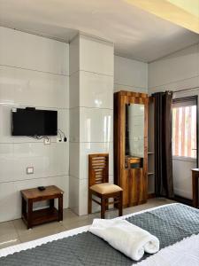 a bedroom with a bed and a tv on the wall at Nest Inn in Suntikoppa