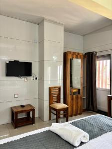 a bedroom with a bed and a tv and a chair at Nest Inn in Suntikoppa