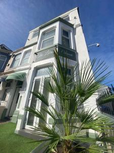 a white building with a palm tree in front of it at The Libra - Adults Only B&B with guaranteed carpark in Blackpool