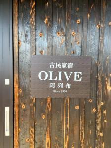 a sign that says olive on a wooden wall at The Kominka-house Olive in Sano