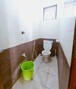 a bathroom with a toilet and a green bucket at Mokaya Investments in Mombasa