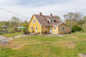 a yellow house with a table and an umbrella at Herrgårdsvillan in Tjurkö