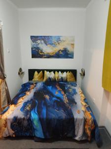 a bed in a bedroom with a painting on the wall at Mia Apartman Salgótarján in Salgótarján