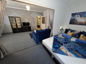 a bedroom with a bed and a couch and a chair at Mia Apartman Salgótarján in Salgótarján