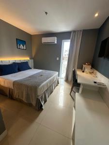 a bedroom with a bed and a desk and a window at Flat Samba Bossa Nova in Cabo Frio +93 photos