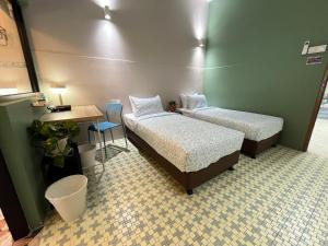 a room with two beds and a table and a desk at Puzzle House in Taiping