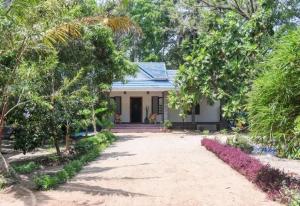 a small white house with trees and a driveway at Marari Bethsaida Homestay in Shertallai