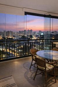 a balcony with a table and chairs and a view of the city at Studio Pôr do Sol - Garagem - Piscina - Anhembi in São Paulo