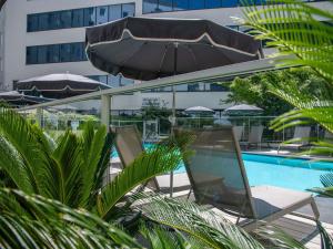 a pool with chairs and umbrellas next to a building at ibis Styles Nice Aéroport Arenas in Nice