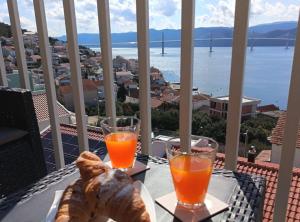 a table with a plate of bread and two glasses of orange juice at Apartment Sutalo with Hot Tub in Komarna